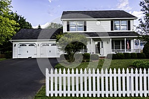 White colonial home with American flag and cat