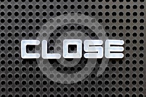 White alphabet with word close on black pegboard background