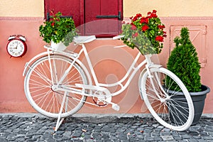 White Color Bicycle And Flower Basket Parked On Old Street