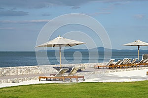 White color recliner beach seating with white parasol facing the