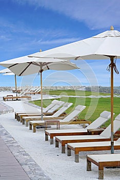 White color recliner beach seating with white parasol facing the