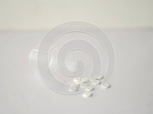 White color tablets pills capsule heap mix therapy drugs with clear plastic glass on white paper