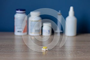 white and colored pills lie on a wooden table against the background of jars with medicines health day