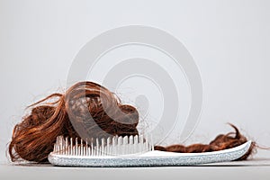 A white comb with false hair. Side view. White background. Copy space. The concept of hair problems and hair care