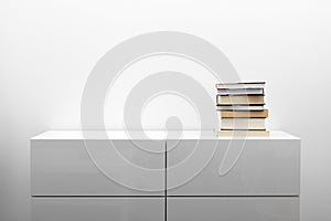 White commode with stack of books in bright minimalism interior