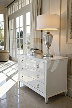 White commode with table lamp in bright minimalism interior