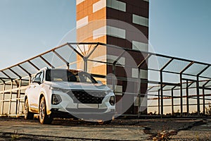 White compact SUV car with sport and modern design parked on concrete road by the sea near the beach at sunset