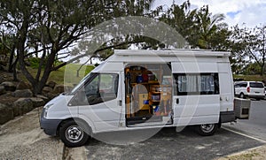 White compact van with household goods in it in a park surrounded by greenery