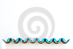 White concrete wall with blue turquoise waves formed by overlapping roof tiles