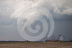 White cone tornado beneath a storm cloud over rural farmland