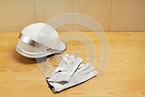 White construction helmet, safety goggles and leather gloves on table