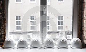 White construction helmets lie on the windowsill in a row inside the building under construction.