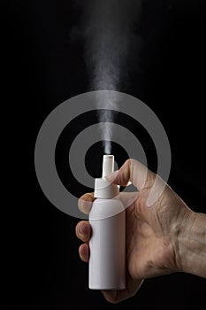 White container of spray bottle on black background