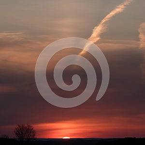 White jet contrail expands with shadow over orange FLX sunset photo