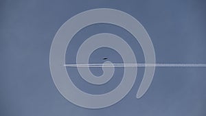 White contrails behind an airplane in a bright, cloudless sky