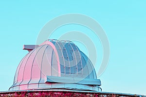 White coral pink dome of a large telescope in the Observatory at sunset on blue pastel sky