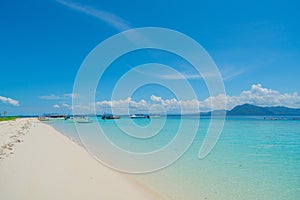 White coral sand beach with moored line-up of boats used to bring tourists to island with moored line-up of boats used to bring