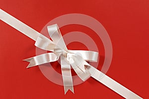 White corner diagonal gift ribbon bow on red paper background