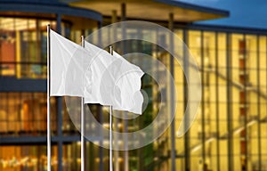 White corporate flags against blurry office building with evening lights