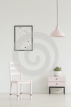 White corridor interior with a chair, cabinet, graphic and lamp.