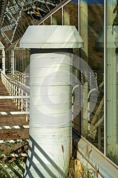 White corrigated metal pipe or tube for ventilation on exterior of building in downtown industrial area of city photo