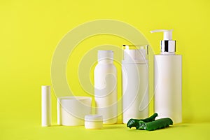 White cosmetic bottles and aloe vera leaves on yellow background. Skin care, body treatment, spa concept