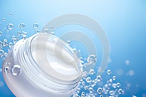 White cosmetic cream jar on blue background with bubbles, drops. Skin care product presentation. Skincare, beauty. Face