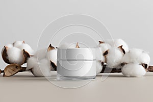 White cosmetic cream jar mockup with a cotton branch on the beige table