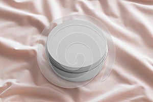 White cosmetic cream jar mockup on the soft pink textile