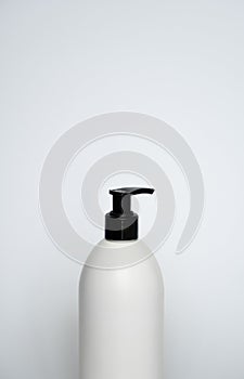 White cosmetic plastic bottle with black pump dispenser on white background. Liquid container for gel, lotion, cream