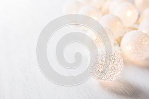 White Cotton Ball Garland with Sparkling Lights on Wood Table. Soft Pastel Colors. Christmas New Year Ornament Decoration.