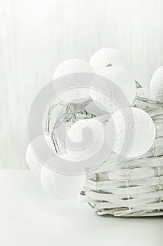 White Cotton Balls Garland in Wicker Basket. Christmas New Year Decoration. Wood Background. Scandinavian Style.