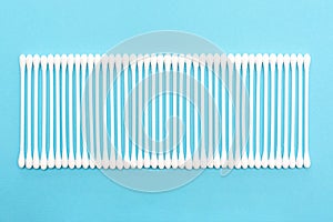 White cotton buds on blue background lie in line