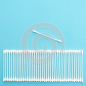 White cotton buds lie in a row on a blue background