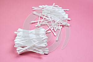 White cotton ear buds on a pink background