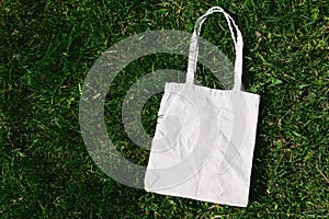 White cotton or mesh eco bag on green grass background. Zero waste, no plastic, eco friendly shopping, recycling concept photo