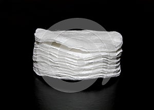 White cotton pads make up remover. Stack of Buds/swabs isolated on black background