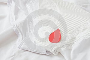 White cotton panties for women with red paper drops like red blood. Concept of menstruation