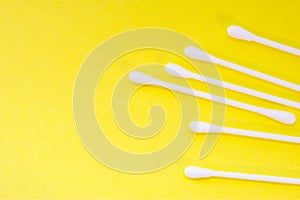 White cotton swabs or buds are on yellow uniform background view from above with clear area of half of photo for labels or headers photo