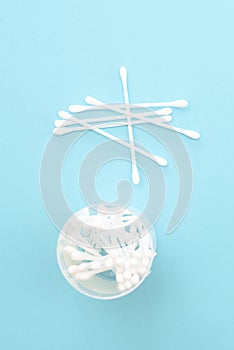 White cotton swabs are in a jar on a blue background. Means of hygiene