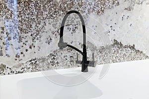 White countertop with sink and black metal faucet in the kitchen