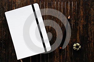 White cover sketchbook with black pencil on rustic wooden table flat lay photo.