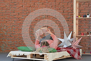 White cozy bed and a beautiful girl, reading a book, concepts of home and comfort, place for text