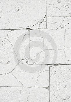 White cracked plaster wall with visible rectangular blocks. The surface is rough with