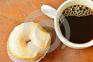 white cream donuts and black coffee cup on wooden board