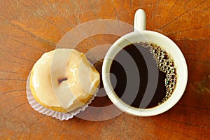 White cream donuts and black coffee cup on wooden board