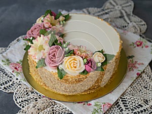 White cream honey cake decorated with buttercream flowers peonies, roses, chrysanthemums, scabiosa on gray background