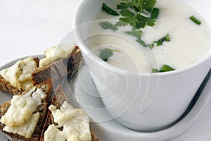 White cream soup with fresh parsley leaves and toast bread