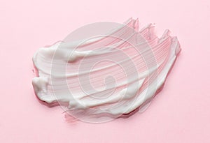 White cream texture, smear over pink background. Cosmetic hydration cream smudge of liquid reach face or body cream