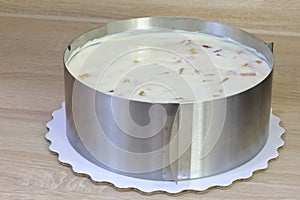 White creamy cake with fruits in metal round shape photo